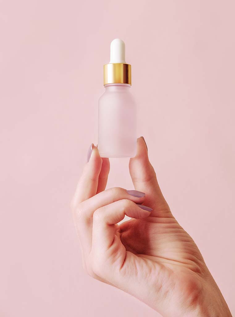 fiole d'un produit de beauté sur un fond rose pastel