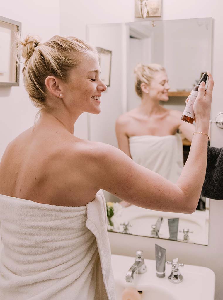 femme blonde qui s'asperge le visage d'une lotion