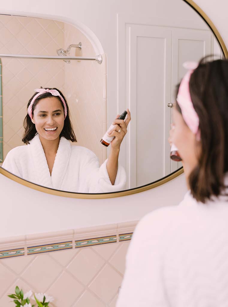femme utilisant un produit de beauté dans sa salle de bains